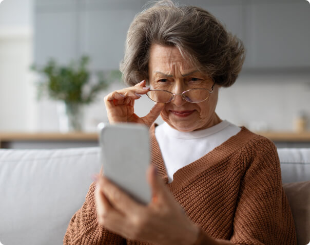 Senior woman holding glasses using her smartphone