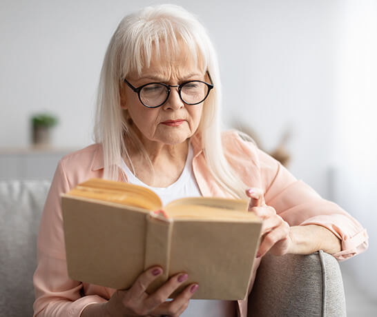 Senior woman wearing glasses and reading a book